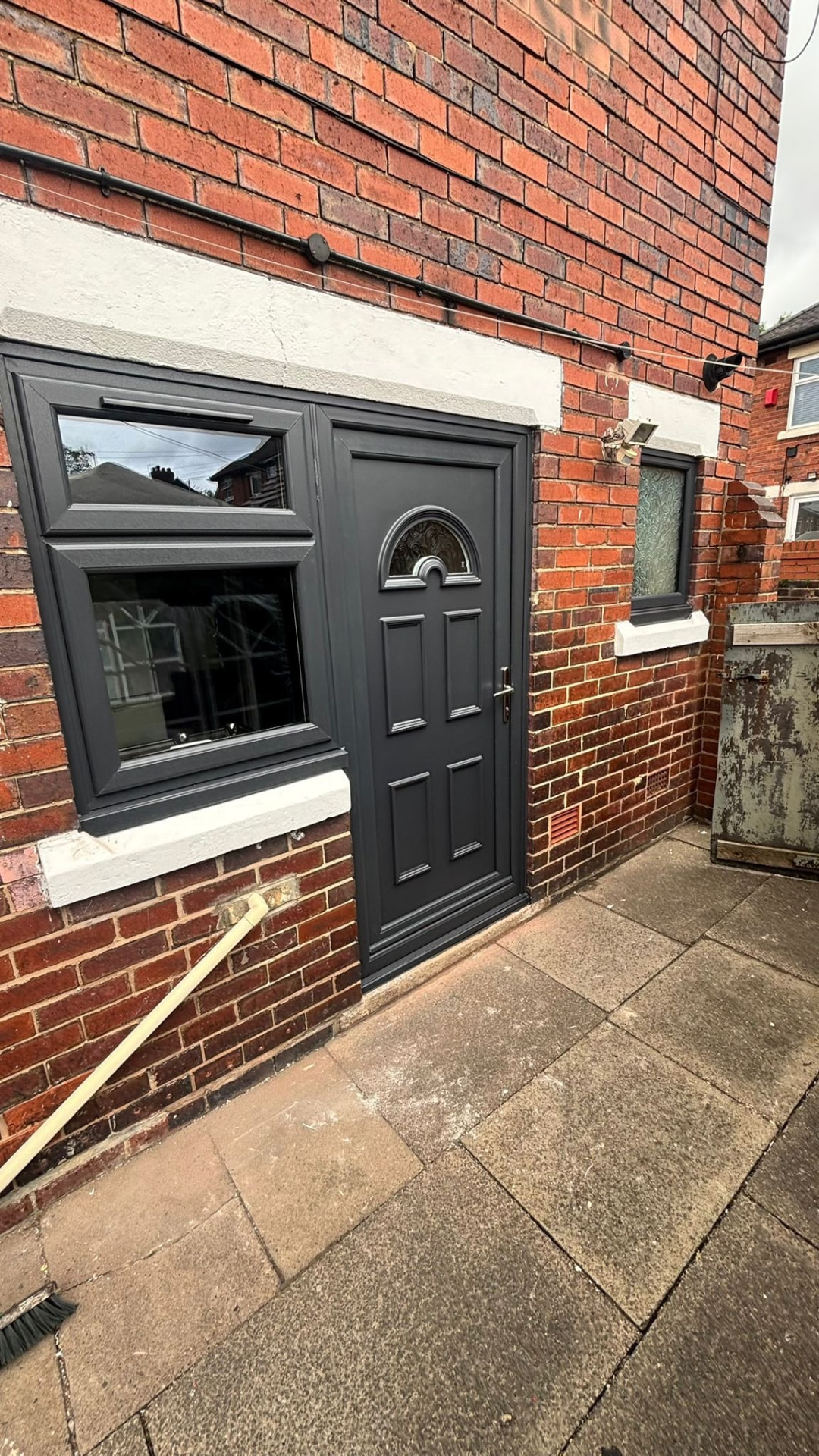 Anthracite grey uPVC door and matching window installed in a red brick wall in Staffordshire