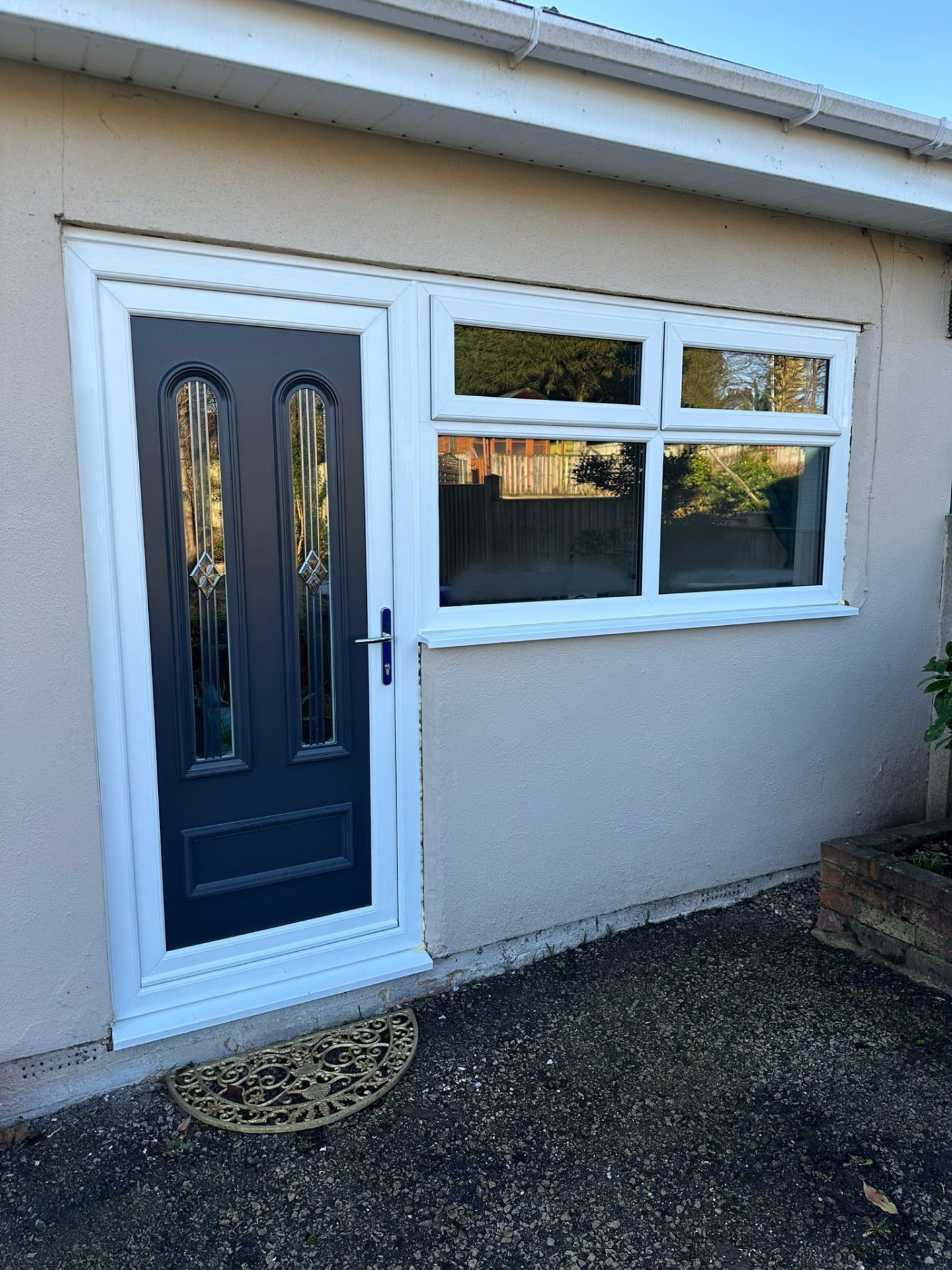 Grey composite door with decorative glass beside a new white uPVC window