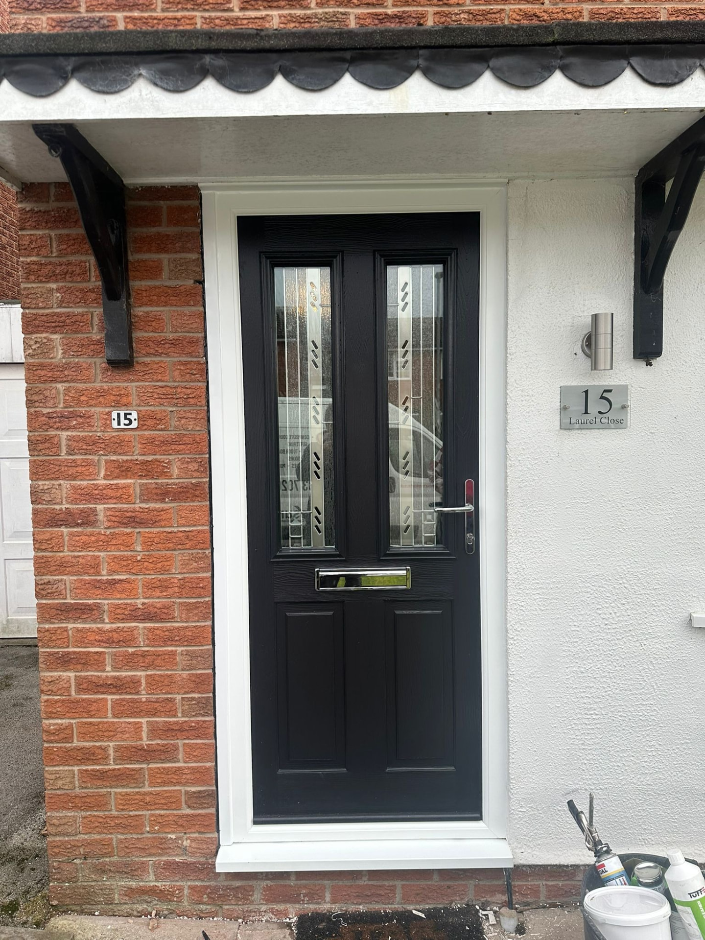 Black composite front door with vertical decorative glass panels fitted to a red brick home in Stoke-on-Trent