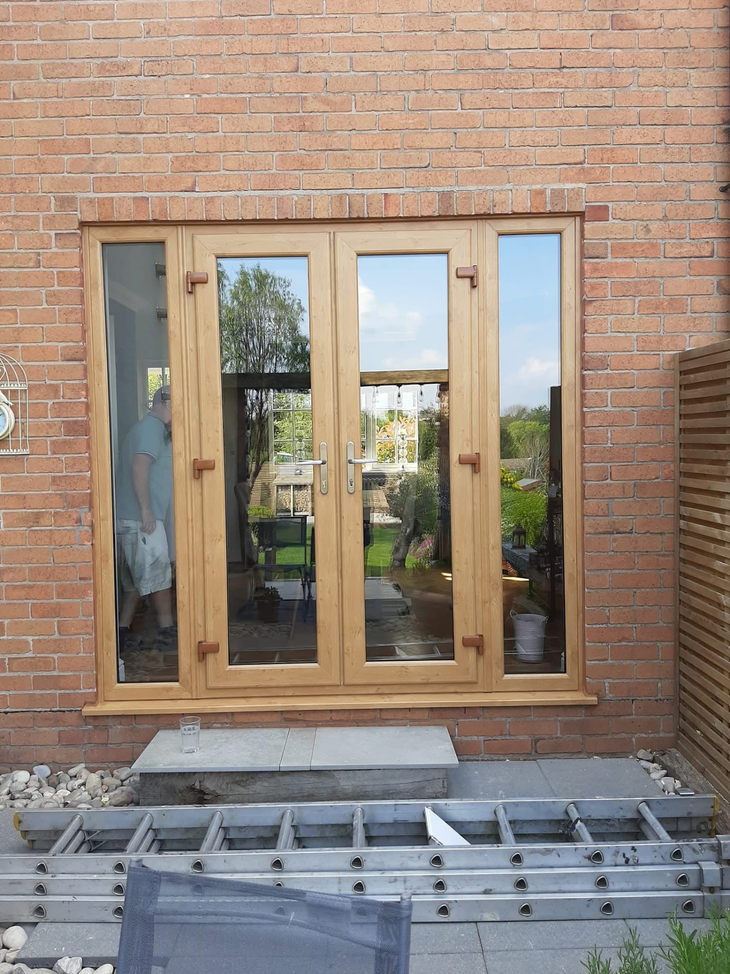 Oak wood-effect uPVC French doors with side panels fitted to a brick home in Cheshire