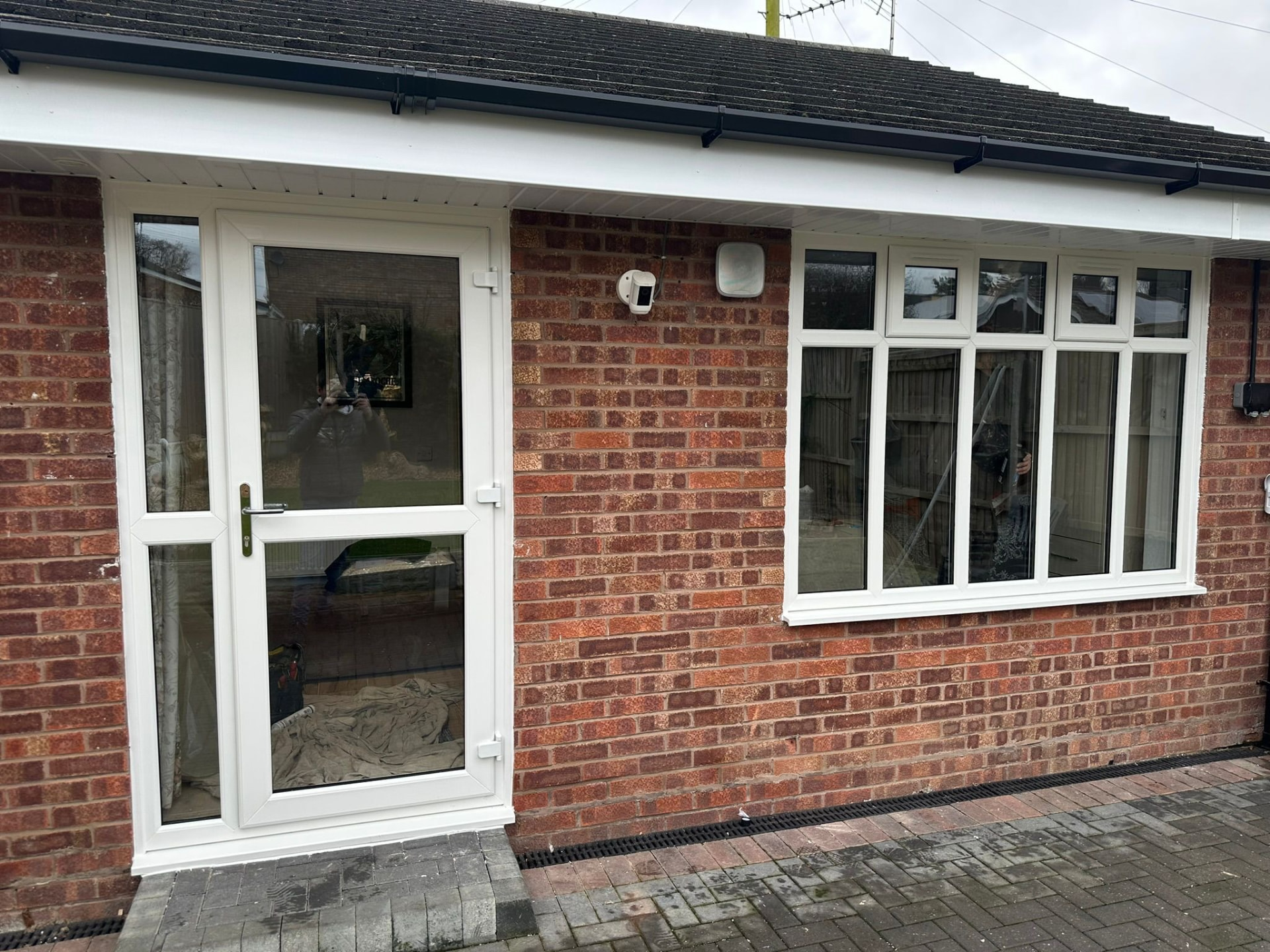 White uPVC entrance door and large multi-pane window installed in a brick property