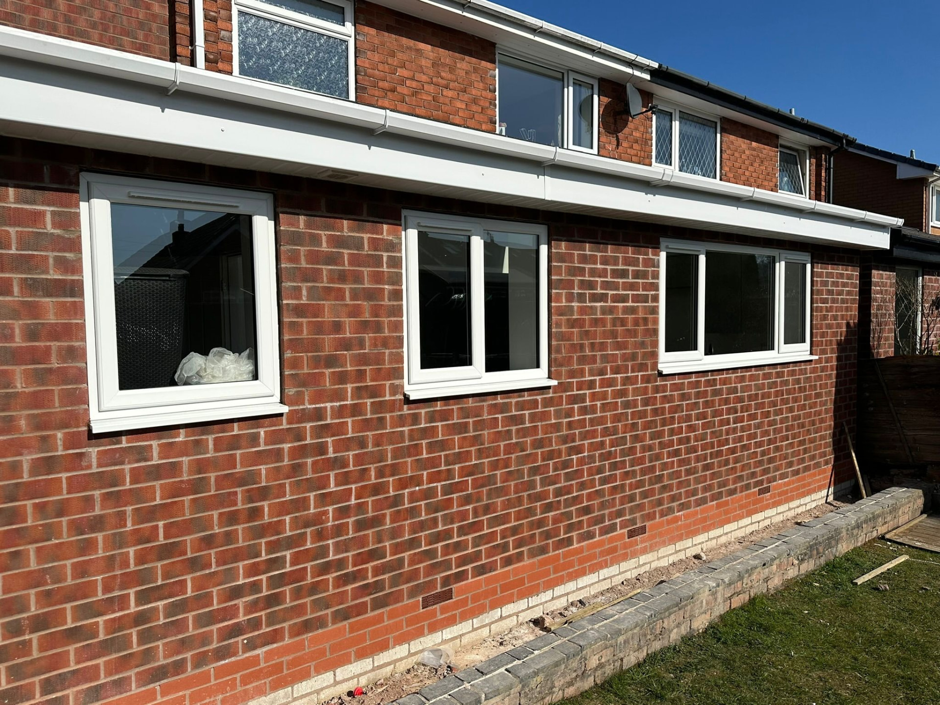Row of three new white uPVC windows fitted to the side of a brick house