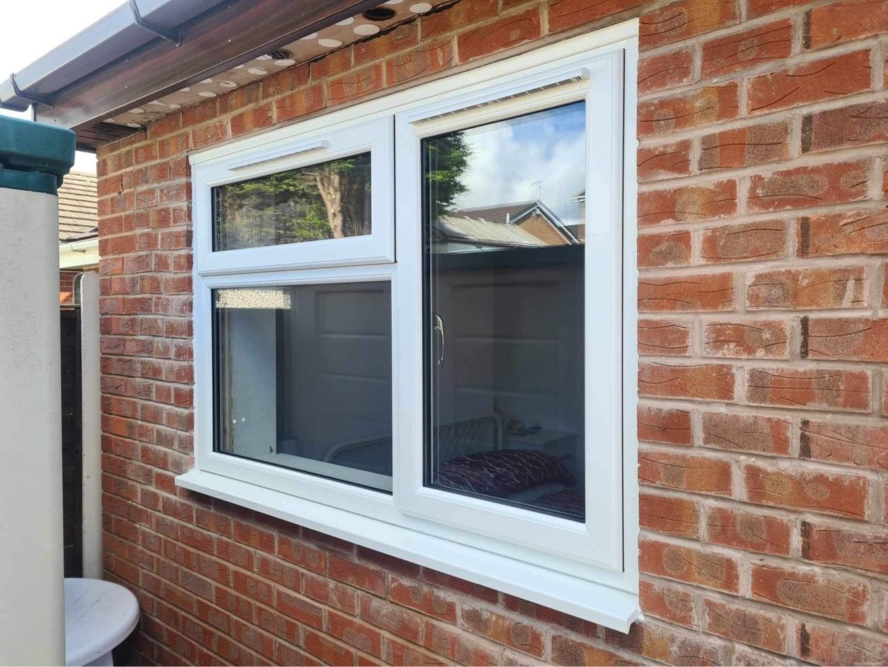 Close-up of a white uPVC window with trickle vents installed in a brick wall