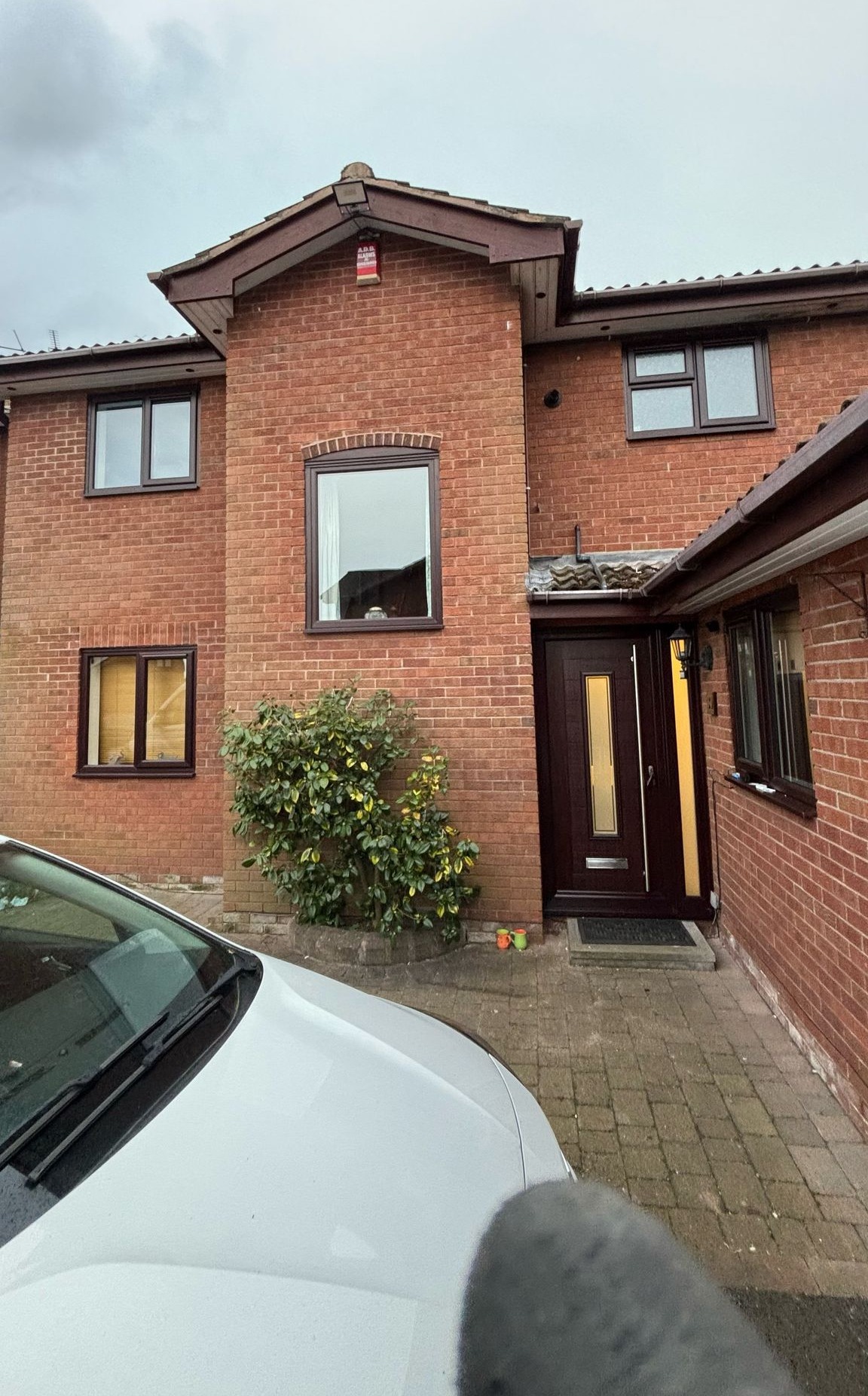 Large brick home with dark wood-effect uPVC windows and matching front door