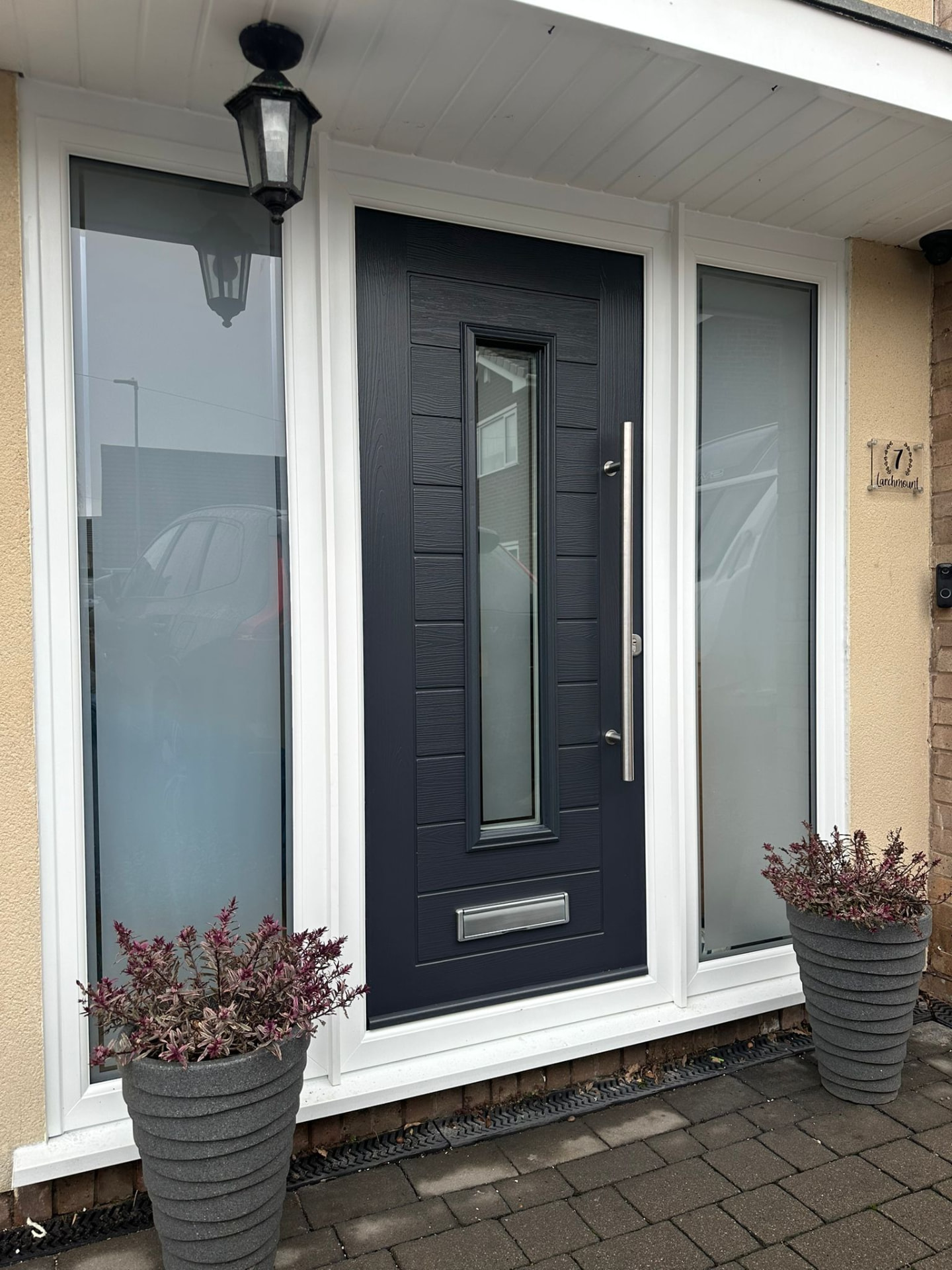 Dark grey contemporary composite door with vertical window and stainless steel bar handle