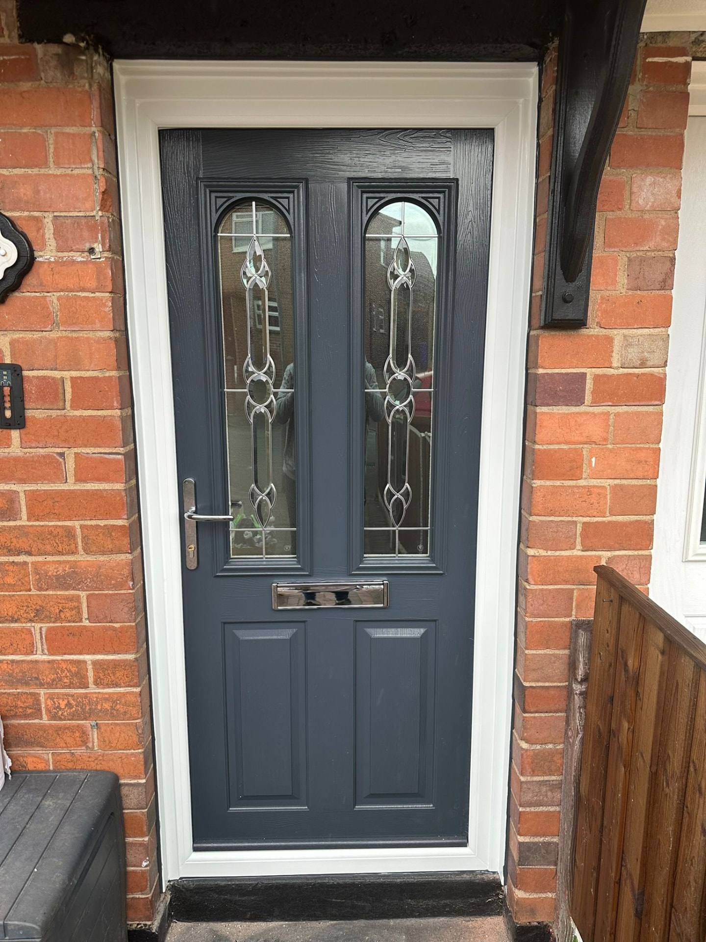 Dark grey composite door with arched decorative glass inserts installed on a local home