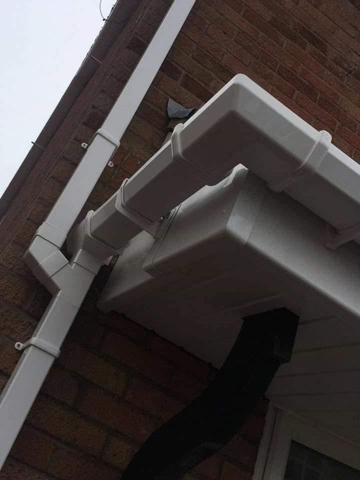Close-up of a white uPVC guttering corner and downpipe installation