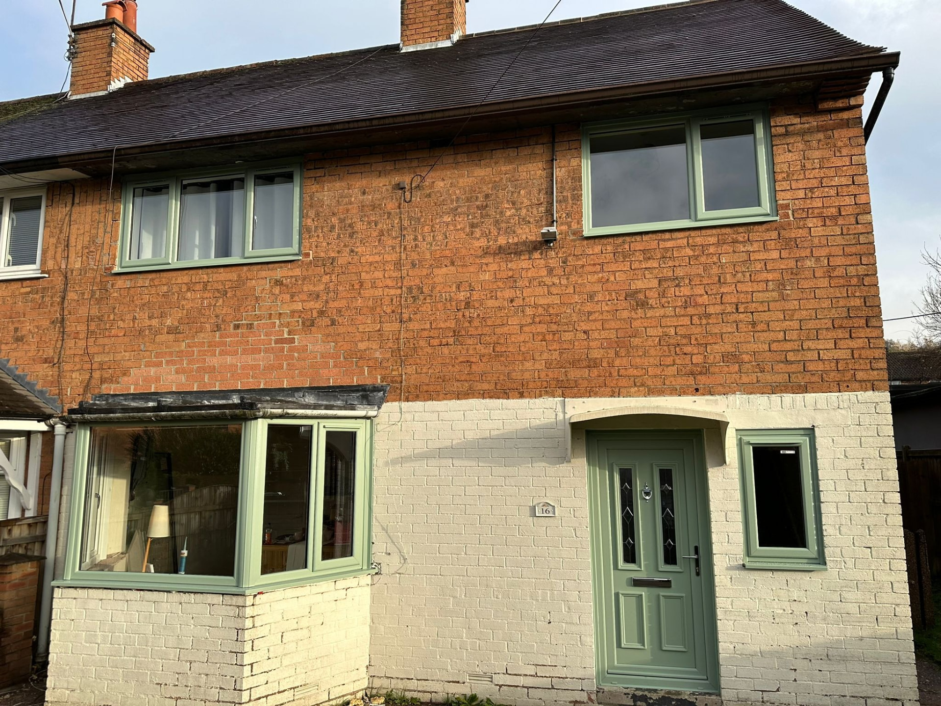 Sage green uPVC windows and matching composite door on a brick and painted home in Staffordshire