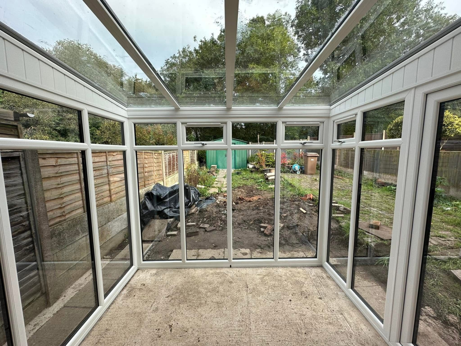 Interior view through a glass-roofed conservatory looking out over the garden